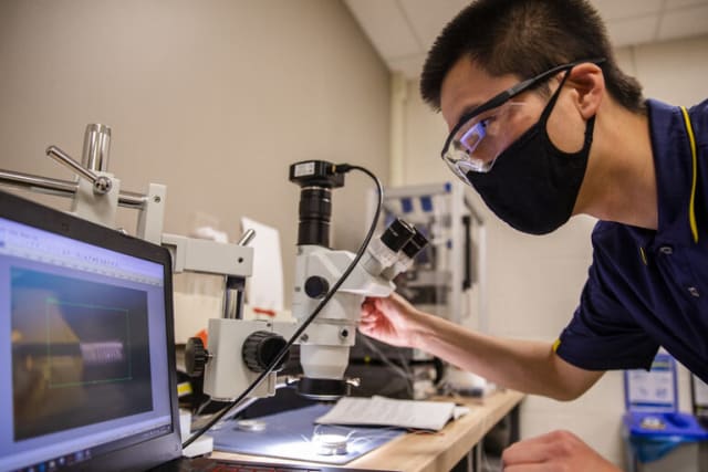 Yi Zhu, graduate student research assistant for civil and environmental engineering, tests the origami microbot. Photo courtesy of the University of Michigan.