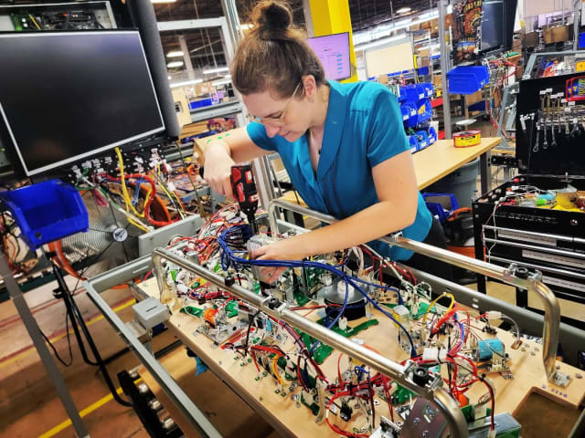 Krystle Gemnich, a production quality technician at Jersey Jack, makes an adjustment before a Toy Story 4 pinball machine playfield moves further down the line. (Image: Jersey Jack Pinball.)